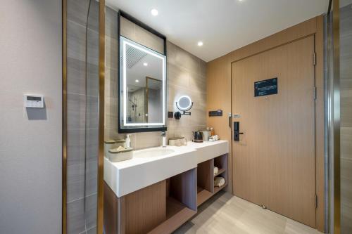ein Badezimmer mit einem weißen Waschbecken und einem Spiegel in der Unterkunft Atour Hotel Shanghai Wujiaochang West Yingao Road Station in Shanghai