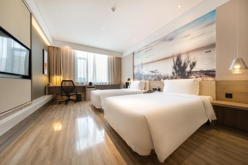 a hotel room with two beds and a television at Atour Hotel Yantai South Station Yingchun Street in Yantai