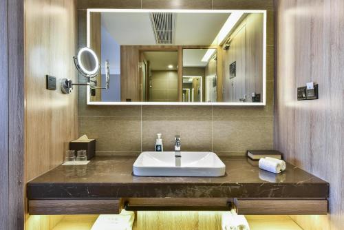 a bathroom with a sink and a mirror at Atour Hotel Tianjin Binhai 1st Street in Binhai