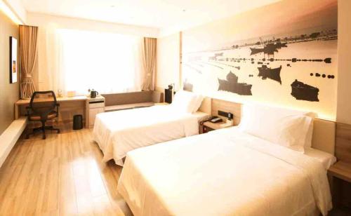 a hotel room with two beds and a desk at Atour Hotel Yantai South Station Yingchun Street in Yantai