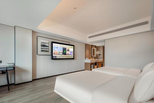 a bedroom with a white bed and a tv on a wall at Atour X Hotel Xiamen SM Plaza District Government in Xiamen
