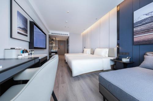 a hotel room with two beds and a sink at Atour Hotel Qingdao Laoshan Shilaoren Beach in Qingdao
