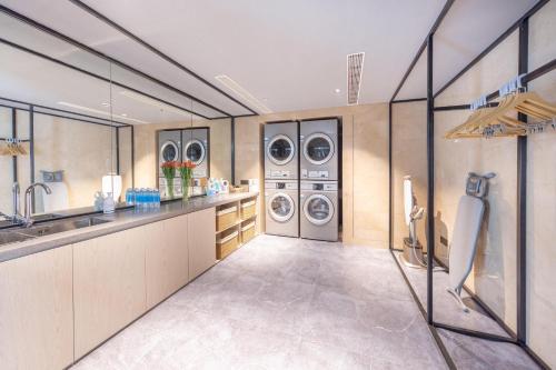 a laundry room with three washing machines and a sink at Atour Hotel Nanjing Jinma Road Station in Nanjing