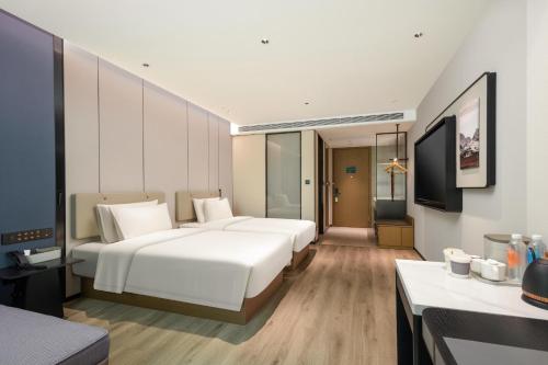 a hotel room with two beds and a television at Atour Hotel Quanzhou Jinjiang Sunshine Plaza in Jinjiang