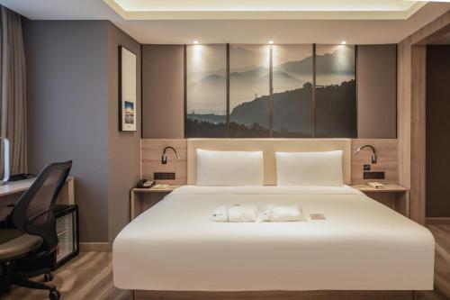 a bedroom with a large white bed and a desk at Atour Hotel Yantai Golden Beach in Yantai