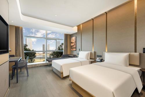 a hotel room with two beds and a television at Atour Hotel Xiamen Meifeng Binhai Romantic Line in Tong'an