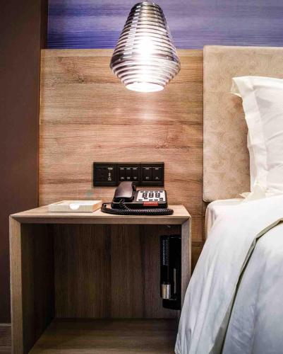 a nightstand with a phone on it next to a bed at Atour Hotel Shenzhen Nanshan Coast City in Shenzhen