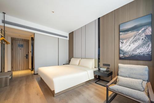 una camera d'albergo con letto e sedia di Atour X Hotel Shanghai Central Bailian Tongchuan Road Station a Shanghai