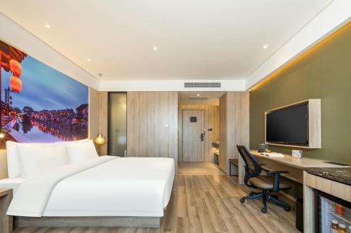 a hotel room with a bed and a desk and a tv at Atour Hotel Shanghai Minhang Industrial Park in Shanghai