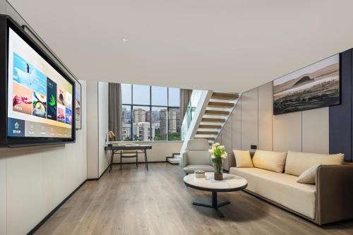 a living room with a couch and a tv at Atour X Hotel Xiamen SM Plaza District Government in Xiamen