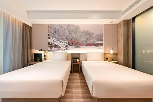 two beds in a hotel room with a painting at Atour Hotel Shenyang South Station Quanyun Road in Shenyang