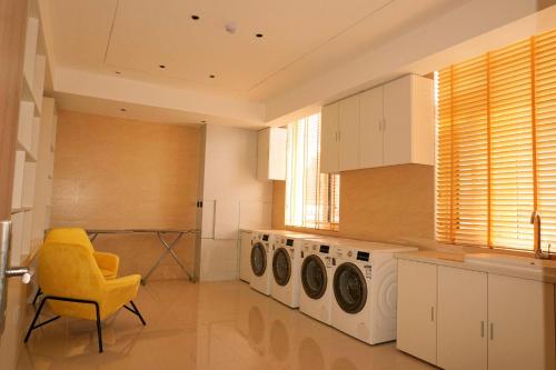 a kitchen with two washing machines and a yellow chair at Atour Hotel Yantai South Station Yingchun Street in Yantai