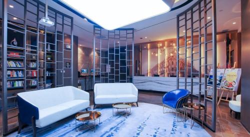 a room with two chairs and a couch and bookshelves at Atour Hotel Harbin Haxi High Speed Railway Station in Harbin