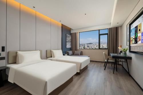 a hotel room with two beds and a desk at Atour Hotel Qingdao Tangdao Bay Jinggangshan Station in Huangdao