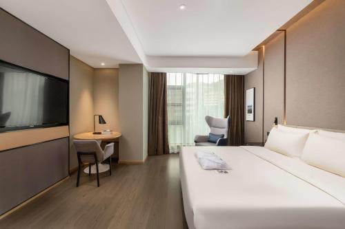 a hotel room with a large bed and a desk at Atour Hotel Chongqing Guanyinqiao Flower Garden in Chongqing