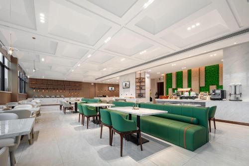 a restaurant with green chairs and tables and a bar at Atour X Hotel Xiamen SM Plaza District Government in Xiamen
