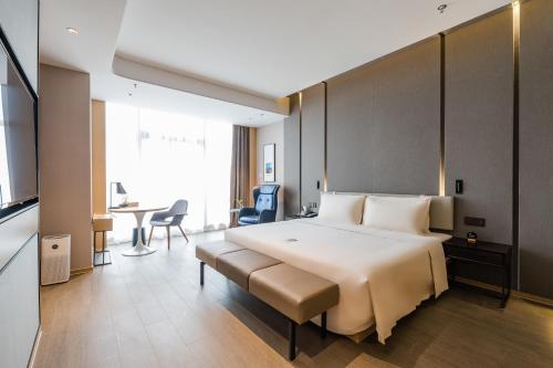 una habitación de hotel con una cama grande y una mesa en Atour Hotel Wuxi Coast City, en Wuxi