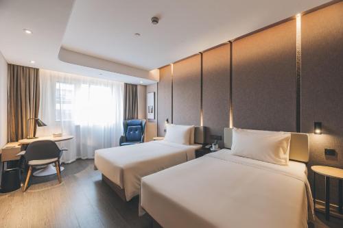 a hotel room with two beds and a desk at Atour Hotel Shanghai Xianxia in Shanghai