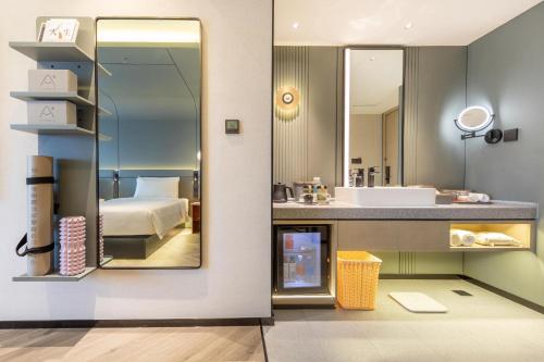 a bathroom with a bed and a sink and a mirror at Atour S Hotel Ningbo Zhoushan East Road in Ningbo