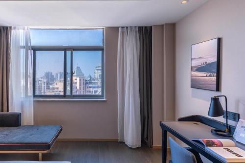 um quarto de hotel com uma secretária e uma janela em Atour Hotel Hefei Pearl Plaza Huijin Business Center em Hefei