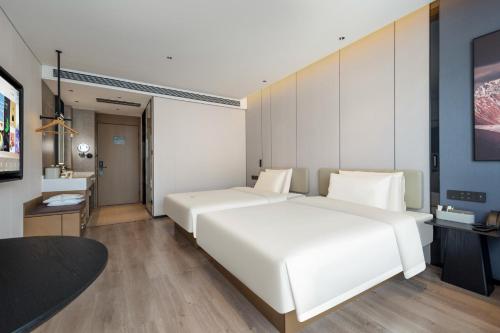 a bedroom with a large white bed and a television at Atour Hotel Zhoushan Putuo Banshengdong Wharf in Zhoushan