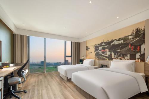 a hotel room with three beds and a desk at Atour Hotel Shanghai Minhang Industrial Park in Shanghai