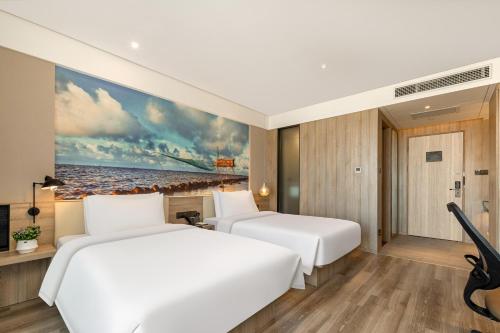 two beds in a hotel room with a painting on the wall at Atour Hotel Shanghai Minhang Industrial Park in Shanghai