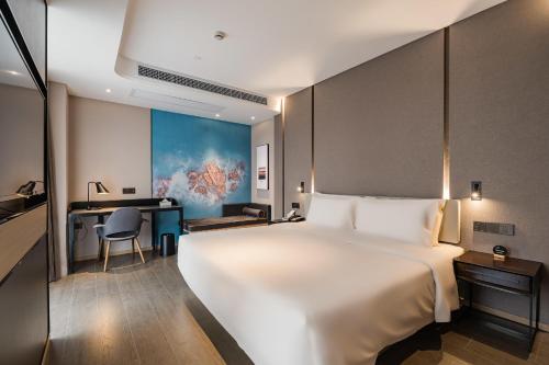 寧波市にあるAtour Hotel Ningbo Yinzhou Impression Cityの大きなベッドとデスクが備わるホテルルームです。