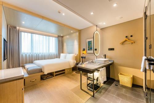 a bathroom with a bed and a sink and a mirror at Atour X Hotel Shanghai Pudong Zhangjiang Park in Shanghai