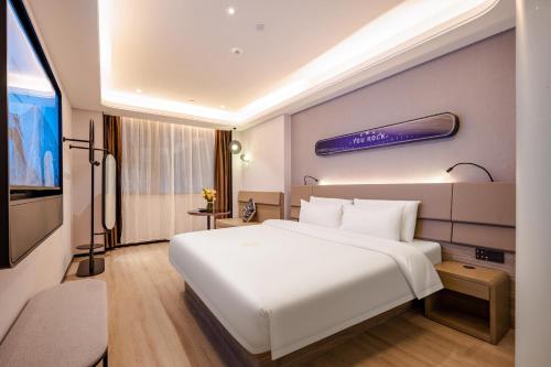 Habitación de hotel con cama blanca grande y TV. en Atour X Hotel Chaozhou Xiangqiao International Financial Business Center, en Chaozhou