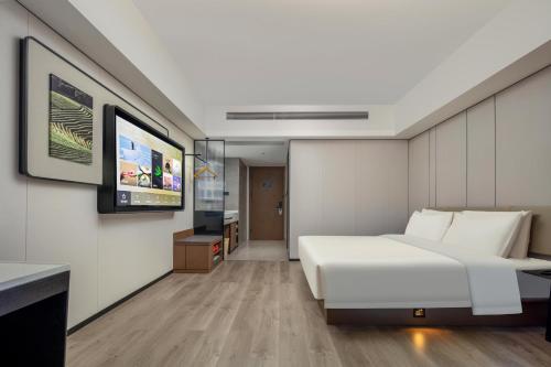 a bedroom with a white bed and a flat screen tv at Atour X Hotel Xiamen SM Plaza District Government in Xiamen