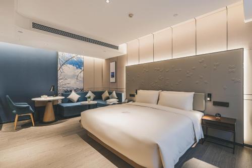um quarto de hotel com uma cama grande e um sofá em Atour S Hotel Chongqing Crown International em Chongqing