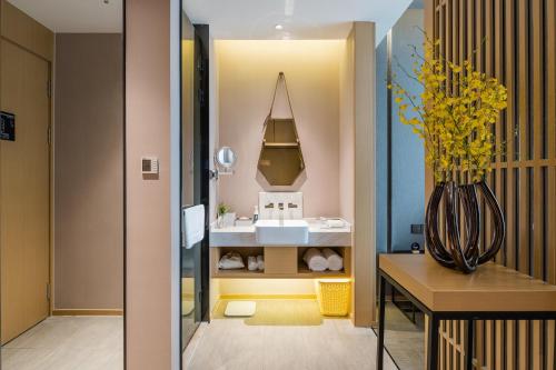 ein Badezimmer mit einem Waschbecken und einer Vase mit gelben Blumen in der Unterkunft Atour Hotel Wuxi Coast City in Wuxi