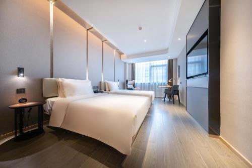 ein Hotelzimmer mit einem großen weißen Bett und einem Schreibtisch in der Unterkunft Atour Hotel Nanchang West Railway Station International Expo City in Nanchang