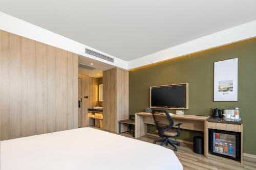 a bedroom with a bed and a desk and a television at Atour Hotel Shanghai Minhang Industrial Park in Shanghai
