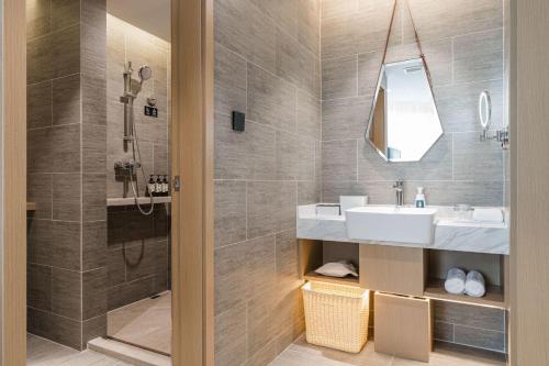 ein Bad mit einem Waschbecken und einer Dusche in der Unterkunft Atour Hotel Ningbo Gulou Tianyige in Ningbo