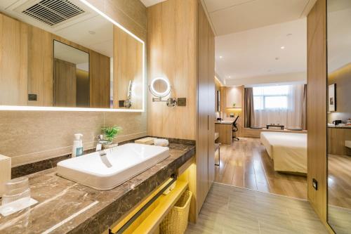 ein Bad mit einem Waschbecken und ein Bett in einem Zimmer in der Unterkunft Atour Hotel Hefei South Station Binhu Convention and Exhibition Center in Hefei