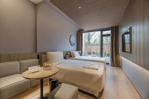 um quarto com uma cama, um sofá e uma mesa em Atour Hotel Shanghai World Expo Center em Xangai