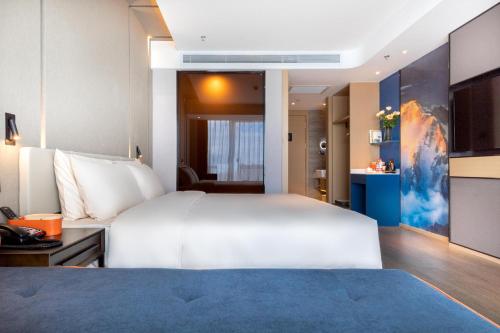 a bedroom with a large white bed and a desk at Atour Hotel Kunming Municipal Government Chunrong Street in Kunming