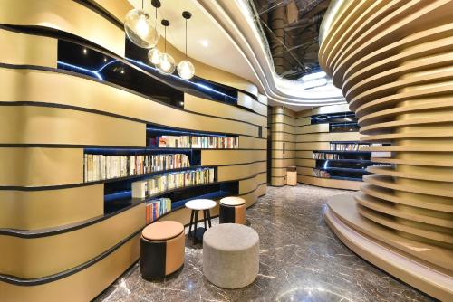 a library with two stools and a wall of books at Atour Hotel Beijing Wangjing 798 Art District in Beijing