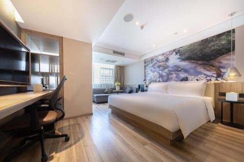 a hotel room with a bed and a desk at Atour Hotel Zhongshan Er Road Lihe Plaza in Zhongshan