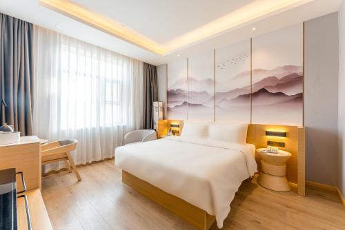 上海市にあるAtour Hotel Shanghai Pudong Jinqiao International Commercial Plazaのベッドとデスクが備わるホテルルームです。