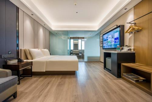 a bedroom with a bed and a flat screen tv at Atour X Hotel Dongguan Chang'an Wanda in Dongguan
