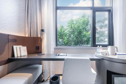 um quarto com uma secretária e uma janela em Atour Light Hotel Kunming Dianchi Road South Asia Style First City em Kunming