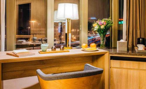 a desk with a lamp and a vase of flowers at Atour Hotel Shanghai Wujiaochang Dabaishu in Shanghai
