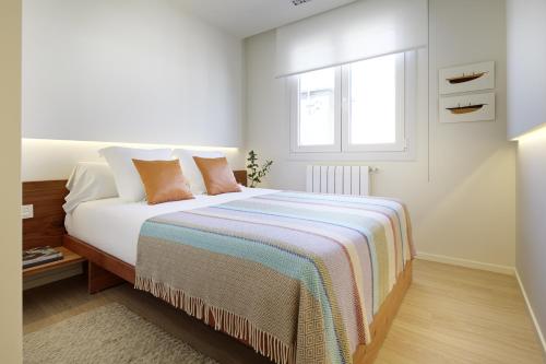 Dormitorio blanco con cama y ventana en Mur by Feelfree Rentals, en San Sebastián