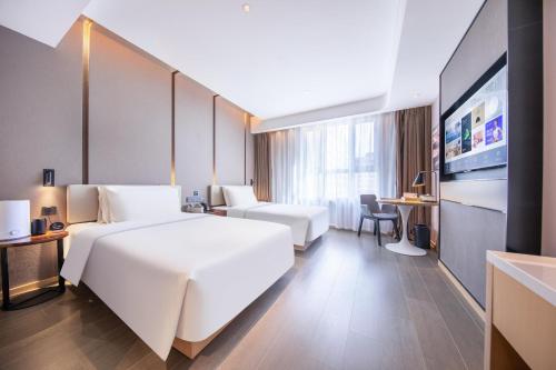 una camera d'albergo con un grande letto bianco e una scrivania di Atour Hotel Urumqi Airport Degang Wanda a Ürümqi