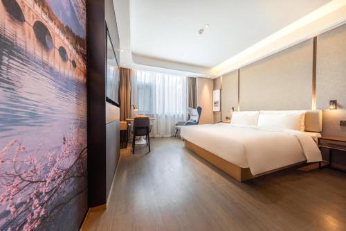a hotel room with a large bed and a painting at Atour Hotel Kunming Cuihu in Kunming