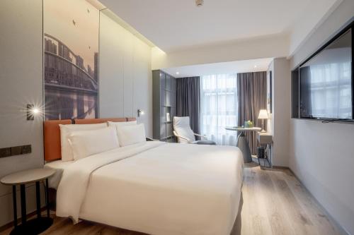 una camera d'albergo con un grande letto bianco e una scrivania di Atour Light Hotel Guiyang Fountain a Guiyang
