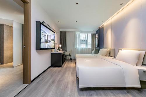 a hotel room with a large white bed and a television at Atour Hotel Quanzhou Hongchang Baozhou Road in Quanzhou